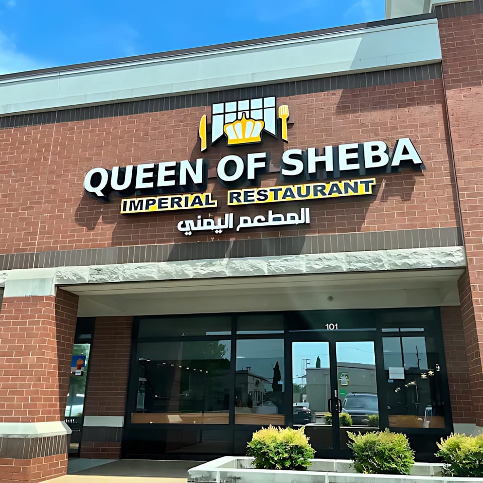 Exterior of Queen of Sheba Imperial Restaurant, a Middle Eastern eatery with a brick facade and large windows.