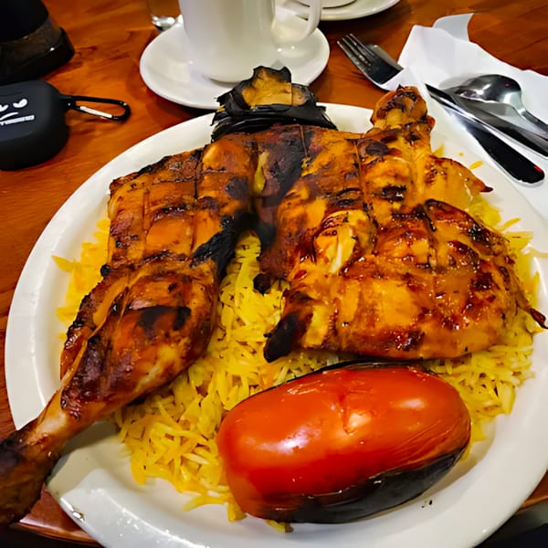 Grilled chicken, yellow rice, and roasted vegetables on a white plate at Queen of Sheba Imperial Restaurant.